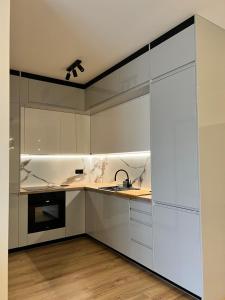 a kitchen with white cabinets and a sink at Apartament w Kębłowie in Kębłowo +12 photos