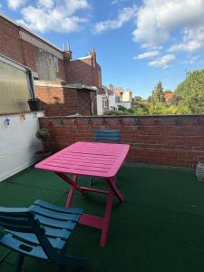 a pink picnic table and two chairs on a patio at Les chtis voyageurs appartement 2 chambres terrasse in Marcq-en-Baroeul