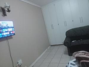 a living room with a couch and a flat screen tv at SkyWags Guest House in Bloemfontein