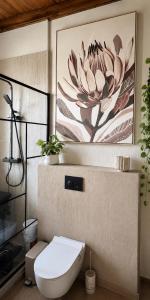 a bathroom with a toilet and a flower painting on the wall at Nordik Crest in Mărişel