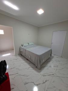 a bedroom with a bed in a room with marble floors at Conforto e Tranquilidade, Casa Completa in Martins