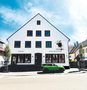 a green car parked in front of a white building at Neros Hotel in Siegenburg