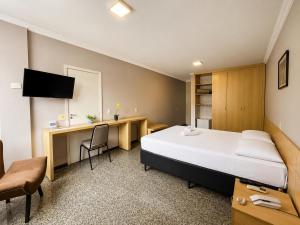 a hotel room with a large bed and a desk at Hotel Diplomat by Bsb Inn in Brasília