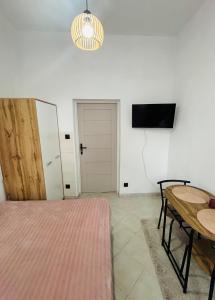 a bedroom with a bed and a table and a tv at Pomarańczowy Domek in Junoszyno