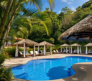 a pool with chairs and umbrellas next to a resort at Hotel Playa Espadilla in Manuel Antonio