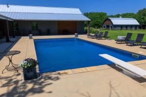 a large blue swimming pool with chairs and a house at Whispering Prairie Lodge in Salina