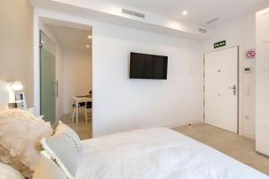 a white bedroom with a bed and a tv on a wall at Maravilloso estudio en pleno centro in Madrid