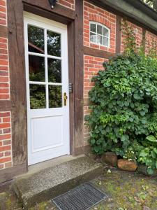 a white door on a brick house with a bush at Lieblingsnest in Bad Fallingbostel