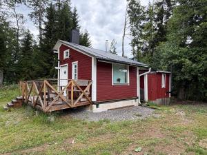 a small red house with a wooden porch in a field at The Hermits Hut in Österby