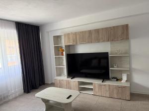 ein Wohnzimmer mit Flachbildfernseher und einem Tisch in der Unterkunft Argeş Central in Curtea de Argeş