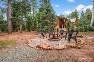 a group of chairs and a fire pit in front of a log cabin at Lovely Log Cabin With Fire Pit! in Duck Creek Village