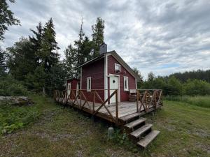 a small red house with a porch and a wooden deck at The Hermits Hut in Österby