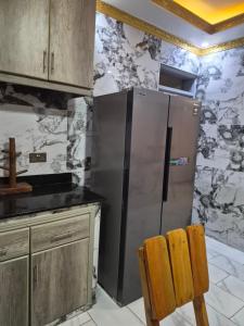 a kitchen with a stainless steel refrigerator and a wooden chair at Pearl Stay in Entebbe