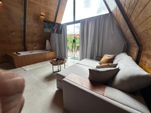 ein großes Zimmer mit Sofa und Badewanne in der Unterkunft Chalé Time stop in Cachoeiras de Macacu