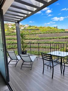 a patio with a table and chairs and a view of a vineyard at Villa Bavaria C in Ponta do Sol