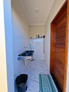 a small bathroom with a sink and a door at Conforto e Tranquilidade, Casa Completa in Martins +8 photos