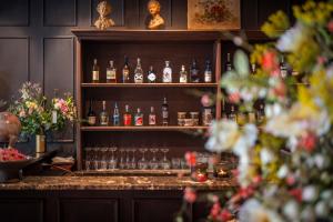 eine Bar mit Flaschen und Gläsern auf einem Regal in der Unterkunft Hotel Cour Saint Georges by CW Hotel Collection in Gent
