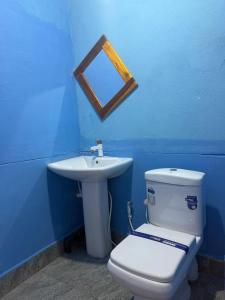 a blue bathroom with a toilet and a sink at Afaa Beach Guest House in Arugam Bay