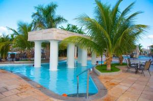 a swimming pool with palm trees in a resort at Lacqua DiRoma - Acesso livre ao Park Aquático - Central de Reservas in Caldas Novas