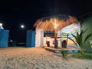 a hut with a straw roof on the beach at night at Afaa Beach Guest House in Arugam Bay