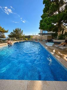 a large blue swimming pool with two people sitting on chairs at Vista Mare Vidikovac in Budva