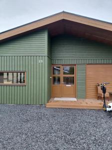 a green building with a brown door and a building at Elliðaár Valley Guesthouse in Reykjavík