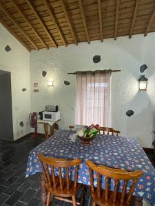 a dining room with a table and chairs and a table and a window at Robalinho's House in Faja Grande