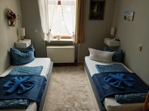 a bedroom with two beds with blue sheets and a window at Gasthaus & Pension Schmidt's in Haldensleben