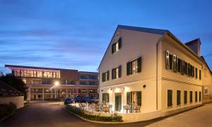 a white building with tables and chairs in front of a building at Aminess Florian & Godler Hotel in Karlovac