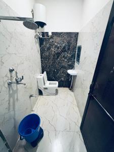 a bathroom with a toilet and a blue bucket at Barsana Geust House in Khātu