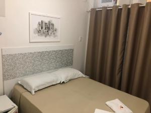 a small bedroom with a bed and a curtain at Hotel Natal in Santos