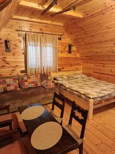 a bedroom with a bed and a couch in a log cabin at Cottage Bosaca in Žabljak