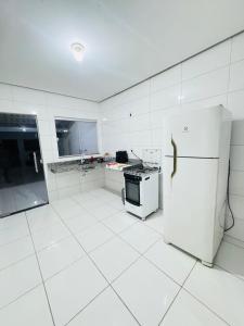 a white kitchen with a stove and a refrigerator at Casa Mobiliada Plus Gurupi in Gurupi