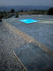 a stone retaining wall with a blue swimming pool at Olivia Suite in Pano Arodes