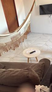 a hammock in a living room with a couch and a table at Pousada Apart Praia Uruaú in Beberibe