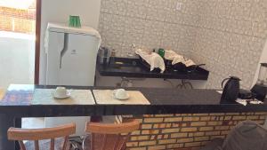 a counter with two chairs and a table with cups on it at Pousada Apart Praia Uruaú in Beberibe +6 photos