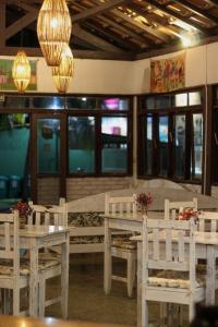 ein Esszimmer mit weißen Tischen und Stühlen und Lampen in der Unterkunft Hotel Vale Verde Coroa Vermelha in Santa Cruz Cabrália
