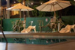 Eine Gruppe von Stühlen und Sonnenschirmen neben einem Pool in der Unterkunft Hotel Vale Verde Coroa Vermelha in Santa Cruz Cabrália