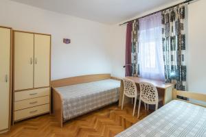 a bedroom with a bed and a desk and a window at Garden Apartments Lustica in Radovici