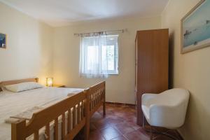 a bedroom with a bed and a chair and a window at Garden Apartments Lustica in Radovici +67 photos