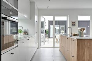 a kitchen with white walls and wooden cabinets at Seaside villa with pool in Simrishamn