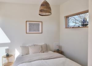 a white bedroom with a bed and a window at Seaside villa with pool in Simrishamn +40 photos