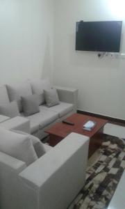 a living room with a couch and a flat screen tv at Qsr Al Balsem Aparthotel in Unayzah