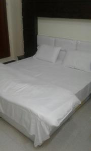 a large white bed with white sheets and pillows at Qsr Al Balsem Aparthotel in Unayzah