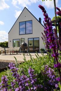 a white house with windows and purple flowers at Seaside villa with pool in Simrishamn