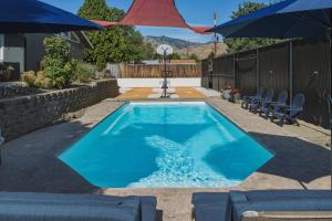 a swimming pool with two chairs and umbrellas at Summer Fun Wenatchee home in Wenatchee