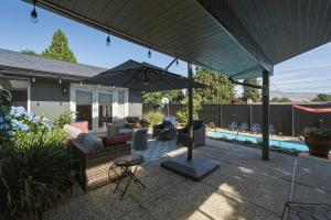 a patio with a couch and an umbrella next to a pool at Summer Fun Wenatchee home in Wenatchee