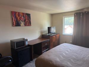 a hotel room with a bed and a desk with a television at Sunshine Motel in Yakima +2 photos
