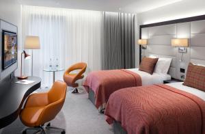 una habitación de hotel con 2 camas y una silla en The Address Connolly en Dublín