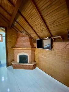 a brick fireplace in a room with a tv at Chales Fazenda Cantinho do Selado in Monte Verde
